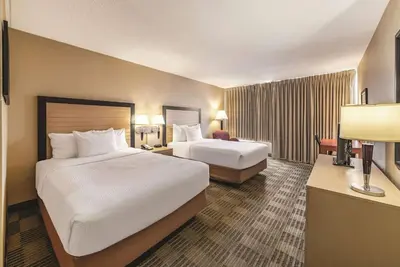 a hotel room with two beds and a desk at Ramada Inn by Wyndham Fairfield NJ in Fairfield