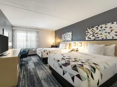 a hotel room with two beds and a desk at Baymont by Wyndham White Plains - Elmsford in Elmsford
