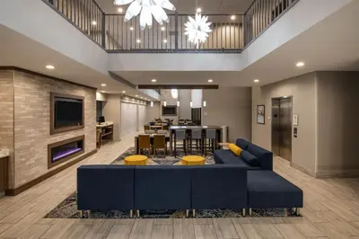 a large living room with a blue couch and a kitchen at Baymont by Wyndham White Plains - Elmsford in Elmsford