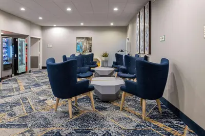 a waiting room with blue chairs and a table at Baymont by Wyndham White Plains - Elmsford in Elmsford