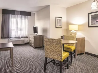 a hotel room with a table and chairs and a television at La Quinta by Wyndham Hartford Bradley Airport in Windsor Locks