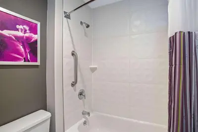 a bathroom with a shower and a white tub at La Quinta by Wyndham Hartford Bradley Airport in Windsor Locks