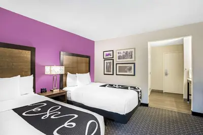a hotel room with two beds and purple walls at La Quinta by Wyndham Hartford Bradley Airport in Windsor Locks