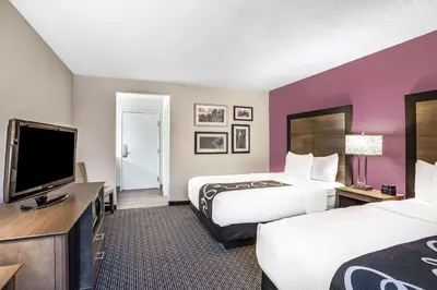 a hotel room with two beds and a flat screen tv at La Quinta by Wyndham Hartford Bradley Airport in Windsor Locks