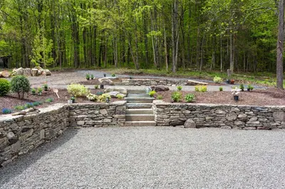 a stone retaining wall with stairs in a garden at Stonehill's Farmhouse in Accord