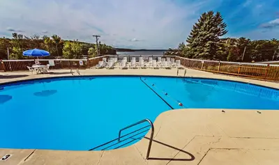 a large blue swimming pool with chairs and a table at Tanglwood Resort in Hawley