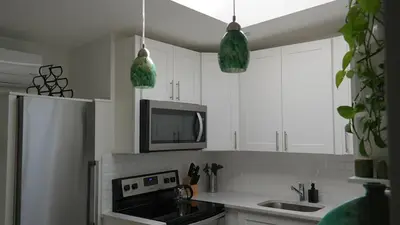a kitchen with white cabinets and a microwave at Sandy's Place NYC 1 in Brooklyn