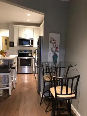 a kitchen with a glass table with chairs and a refrigerator at Sandy's Place NYC 1 in Brooklyn