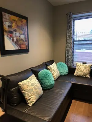 a leather couch with pillows sitting in a living room at Sandy's Place NYC 1 in Brooklyn