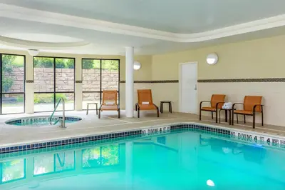 a pool in a hotel room with chairs and a table at Courtyard by Marriott Oneonta in Oneonta