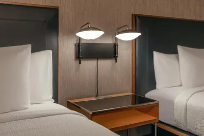 a room with two beds and a tv on the wall at Courtyard by Marriott Oneonta in Oneonta