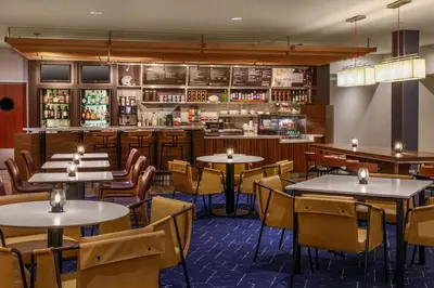 a restaurant with tables and chairs and a bar at Courtyard by Marriott Oneonta in Oneonta