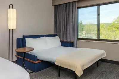 a hotel room with a bed and a window at Courtyard by Marriott Oneonta in Oneonta