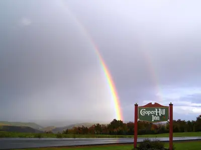 a rainbow in the sky with a sign next to a road at Cooper Hill Inn in West Dover