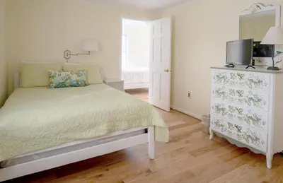 a white bedroom with a bed and a dresser at Cooper Hill Inn in West Dover