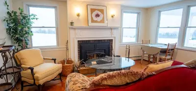 a living room with a fireplace and a table and chairs at Cooper Hill Inn in West Dover