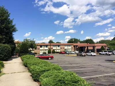 a parking lot with cars parked in front of a building at Travelodge by Wyndham Vernon CT in Vernon