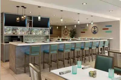 a restaurant with a bar with chairs and tables at Hilton Garden Inn Stony Brook in Stony Brook