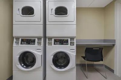 three washing machines in a laundry room with a chair at SpringHill Suites by Marriott Tuckahoe Westchester County in Tuckahoe
