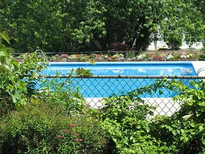 a blue swimming pool in a garden with plants at Interlaken Inn in Lakeville