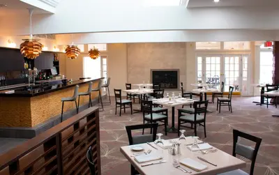a restaurant with tables and chairs and a bar at Interlaken Inn in Lakeville