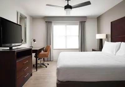a bedroom with a bed and a desk with a television at Homewood Suites by Hilton Carle Place - Garden City, NY in Carle Place