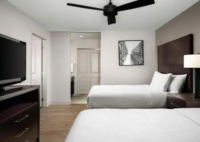 a bedroom with two beds and a flat screen tv at Homewood Suites by Hilton Carle Place - Garden City, NY in Carle Place