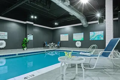a swimming pool with chairs and a table next to it at The Armon Stamford Hotel & Conference Center in Stamford