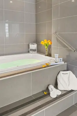 a bathroom with a tub and a vase of flowers at The Armon Stamford Hotel & Conference Center in Stamford