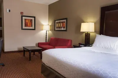 a hotel room with a bed and a red chair at Holiday Inn Express Hartford-Newington by IHG in Newington