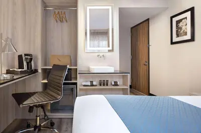 a bedroom with a bed and a chair and a sink at Wingate by Wyndham New York Midtown South/5th Ave in New York