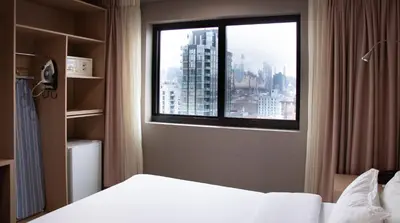 a bedroom with a window with a view of a city at LIC Plaza Hotel in Queens