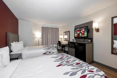 a hotel room with two beds and a flat screen tv at Red Roof Inn Clifton Park in Clifton Park