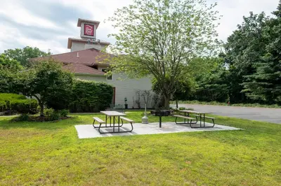 two picnic tables and a clock tower in a park at Red Roof Inn Clifton Park in Clifton Park