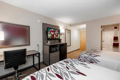a hotel room with a bed and a flat screen tv at Red Roof Inn Clifton Park in Clifton Park