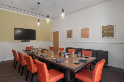 a conference room with a long table and orange chairs at The Williams Inn in Williamstown