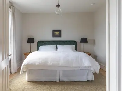 a bedroom with a white bed with a green headboard at Stewart House Hotel in Athens