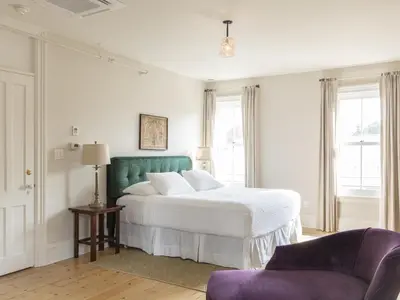 a white bedroom with a bed and a chair at Stewart House Hotel in Athens