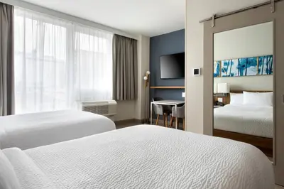a hotel room with two beds and a desk at TownePlace Suites by Marriott New York Long Island City in Queens