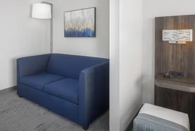 a blue couch in a room with a table at Holiday Inn Express - Ludlow - Chicopee Area by IHG in Ludlow