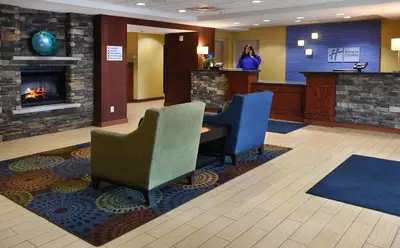 a hotel lobby with a fireplace and a woman standing at a counter at Holiday Inn Express Milford by IHG in Milford