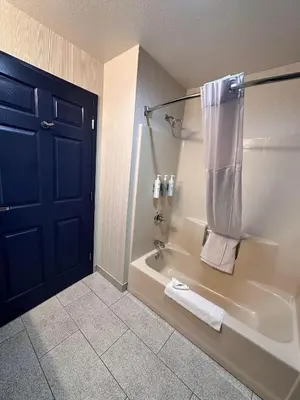 a bathroom with a tub and a shower with towels at Spark by Hilton Guilford in Guilford
