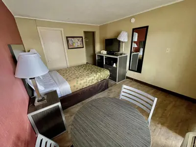 a hotel room with a bed and a table and chair at Economy Inn in East Hartford