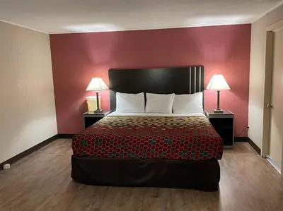 a bedroom with a bed with red walls and two lamps at Economy Inn in East Hartford