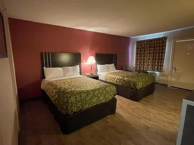 a hotel room with two beds and a red wall at Economy Inn in East Hartford