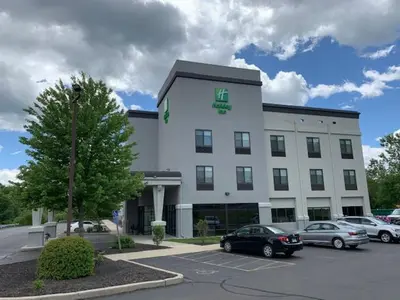 a large white building with cars parked in a parking lot at Holiday Inn Cheshire - Southington by IHG in Southington