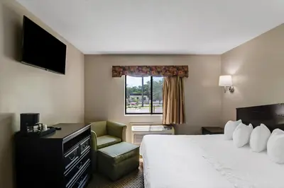 a hotel room with a bed and a chair and a window at Americas Best Value Inn Torrington, CT in Torrington