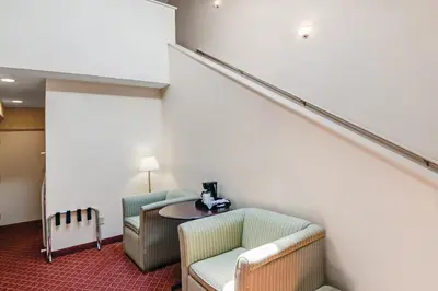 a room with two chairs and a table and stairs at Americas Best Value Inn Torrington, CT in Torrington