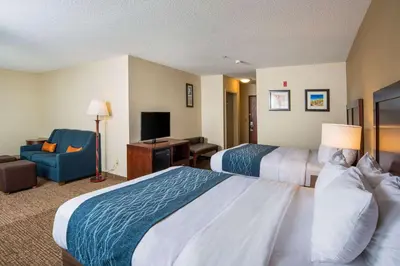 a hotel room with two beds and a chair at Comfort Inn Naugatuck-Shelton, CT in Naugatuck