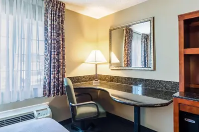 a hotel room with a desk and a mirror at Quality Inn Chicopee-Springfield in Chicopee